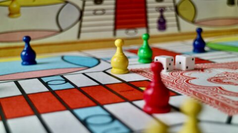 Four modern board games arranged on a table, showing active player interaction and trading mechanics, with a focus on Catan trading problem solutions.